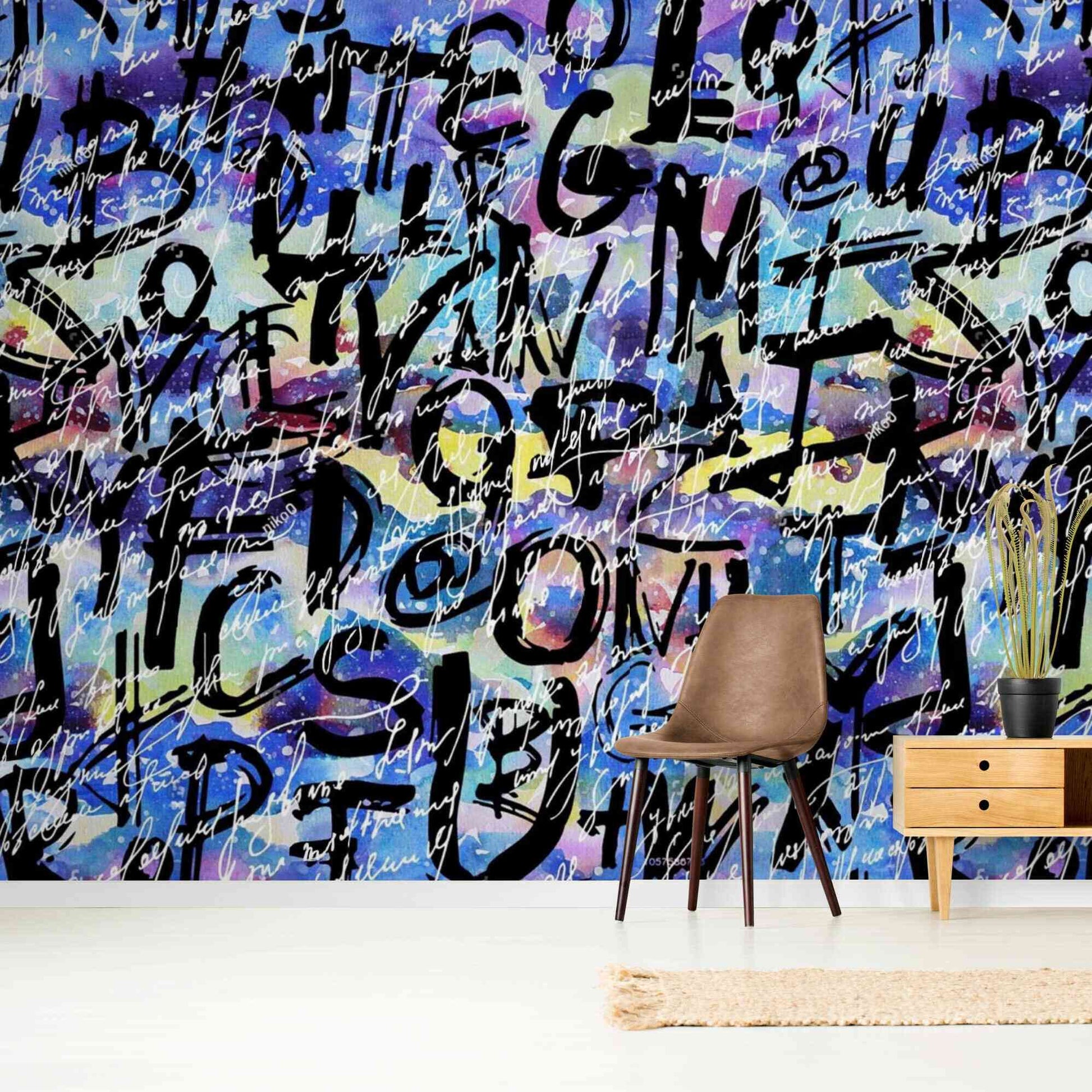 A close-up image of a wallpaper with a blue background and a graffiti-inspired design in shades of white and black. The pattern consists of irregular shapes and lines, creating a chaotic yet artistic effect. The wallpaper is peel and stick, making it easy to install and remove without damaging the wall surface.