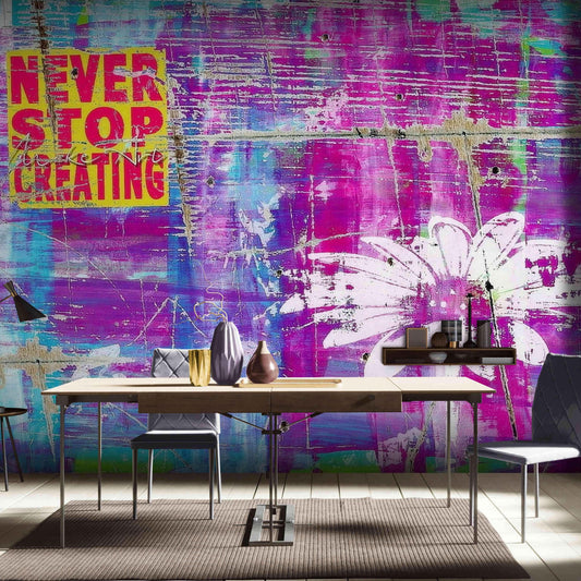 Never Stop Creating" mantra in bold graffiti on a purple wallpaper background